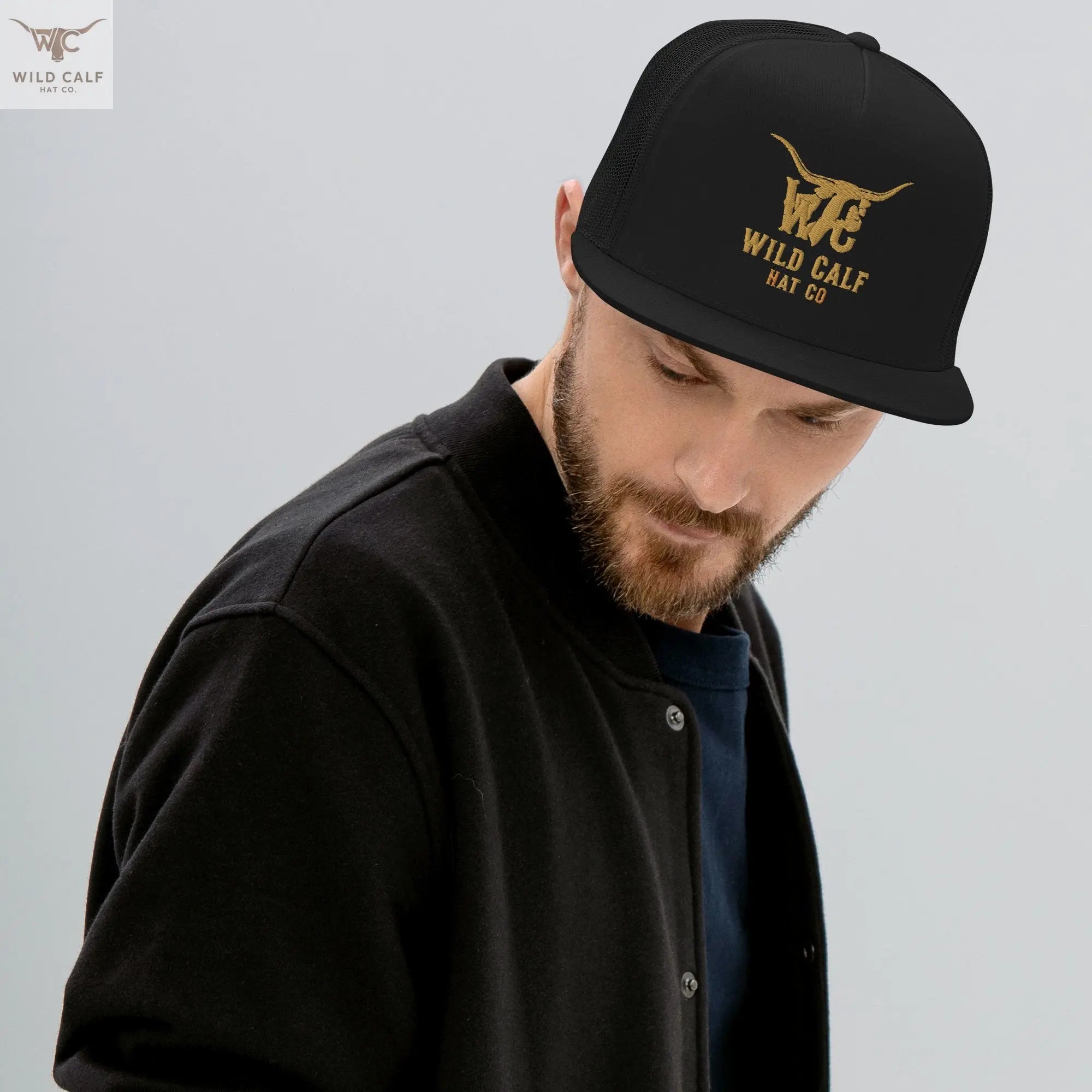 Man wearing a black 5-panel trucker cap with gold western logo, modern professional style