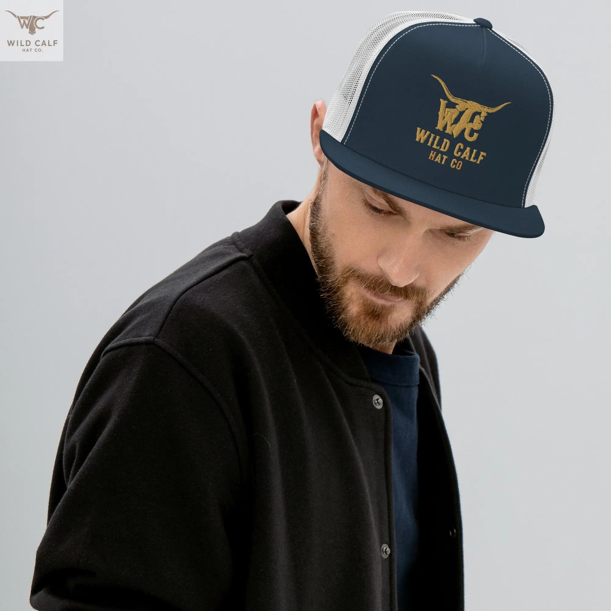 Man wearing navy and white western-style trucker cap with gold embroidered logo