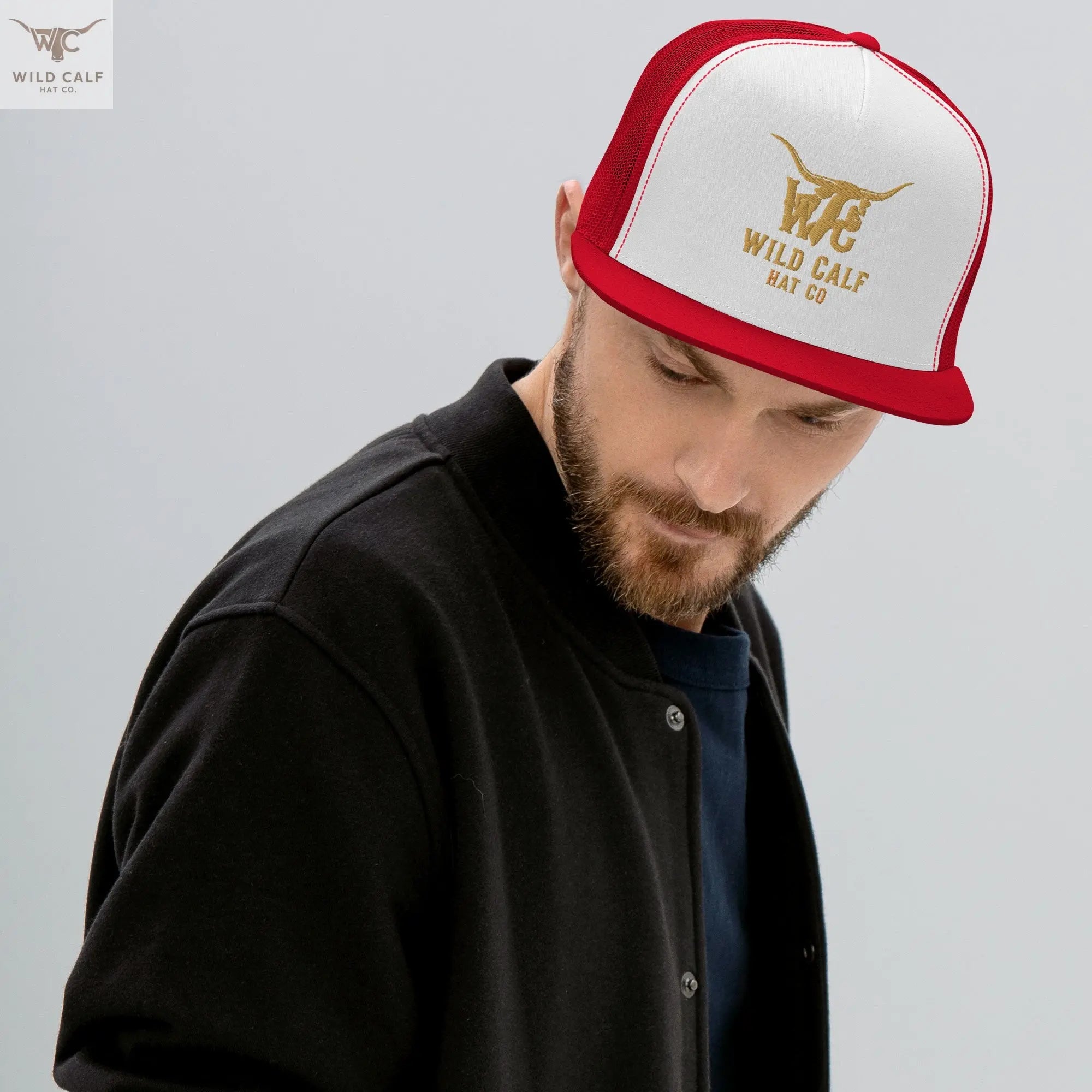 Western style red and white trucker cap with gold bull logo, worn by a bearded man