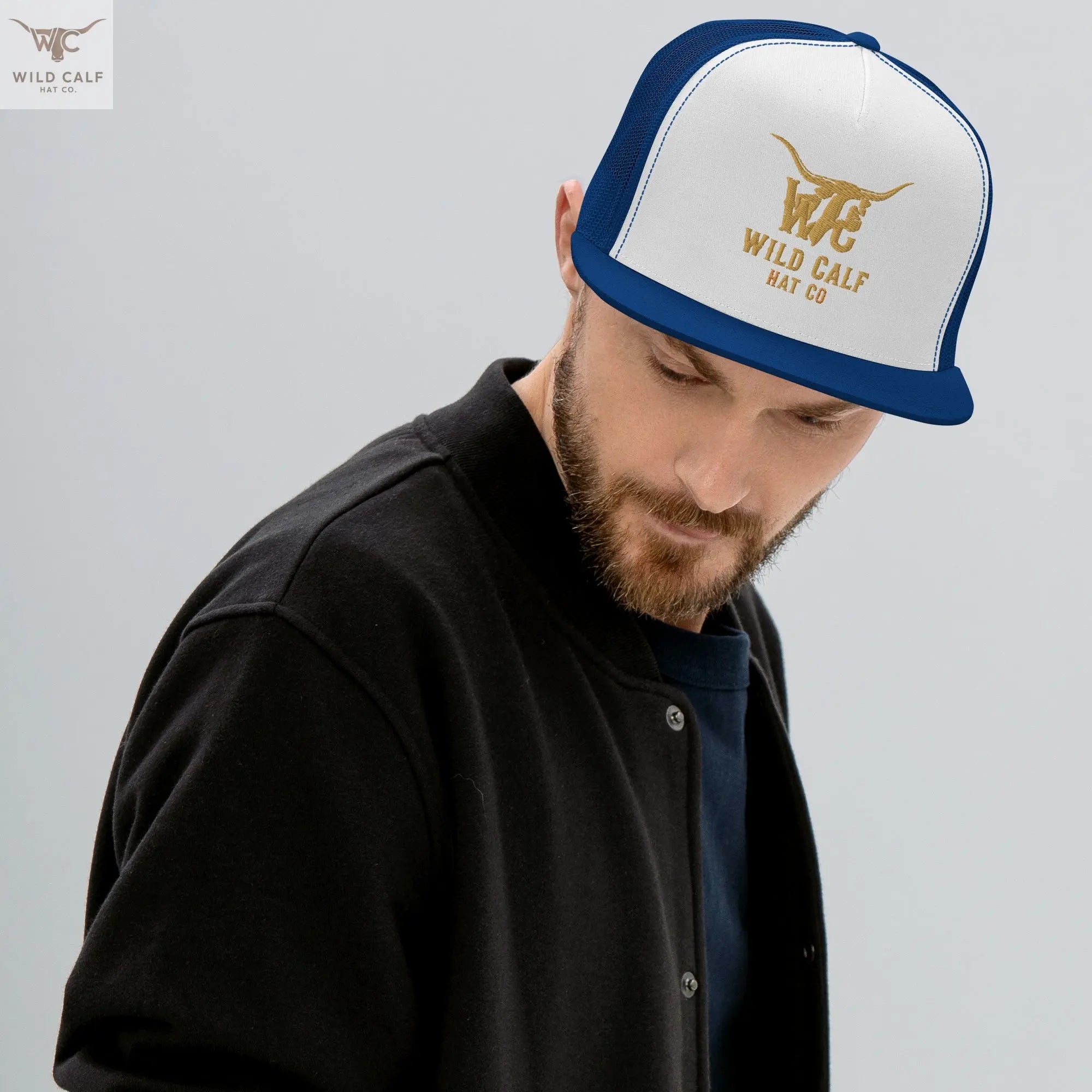 Man wearing a royal blue and white western 5-panel trucker cap with steer logo