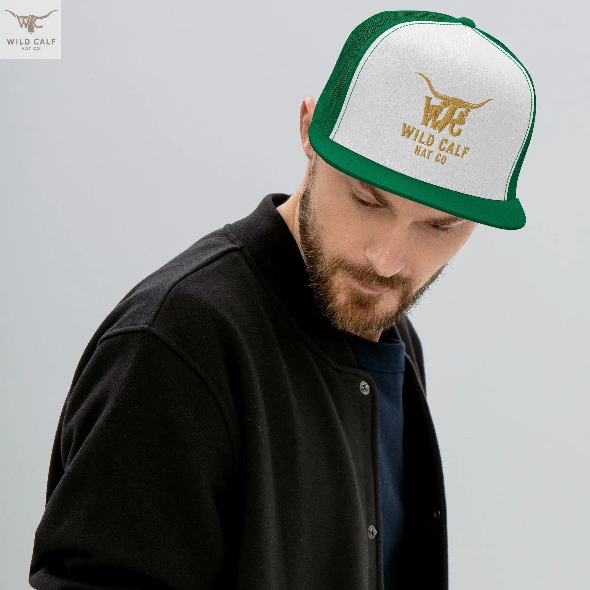 Man wearing a green and white western trucker cap with gold embroidered longhorn logo.