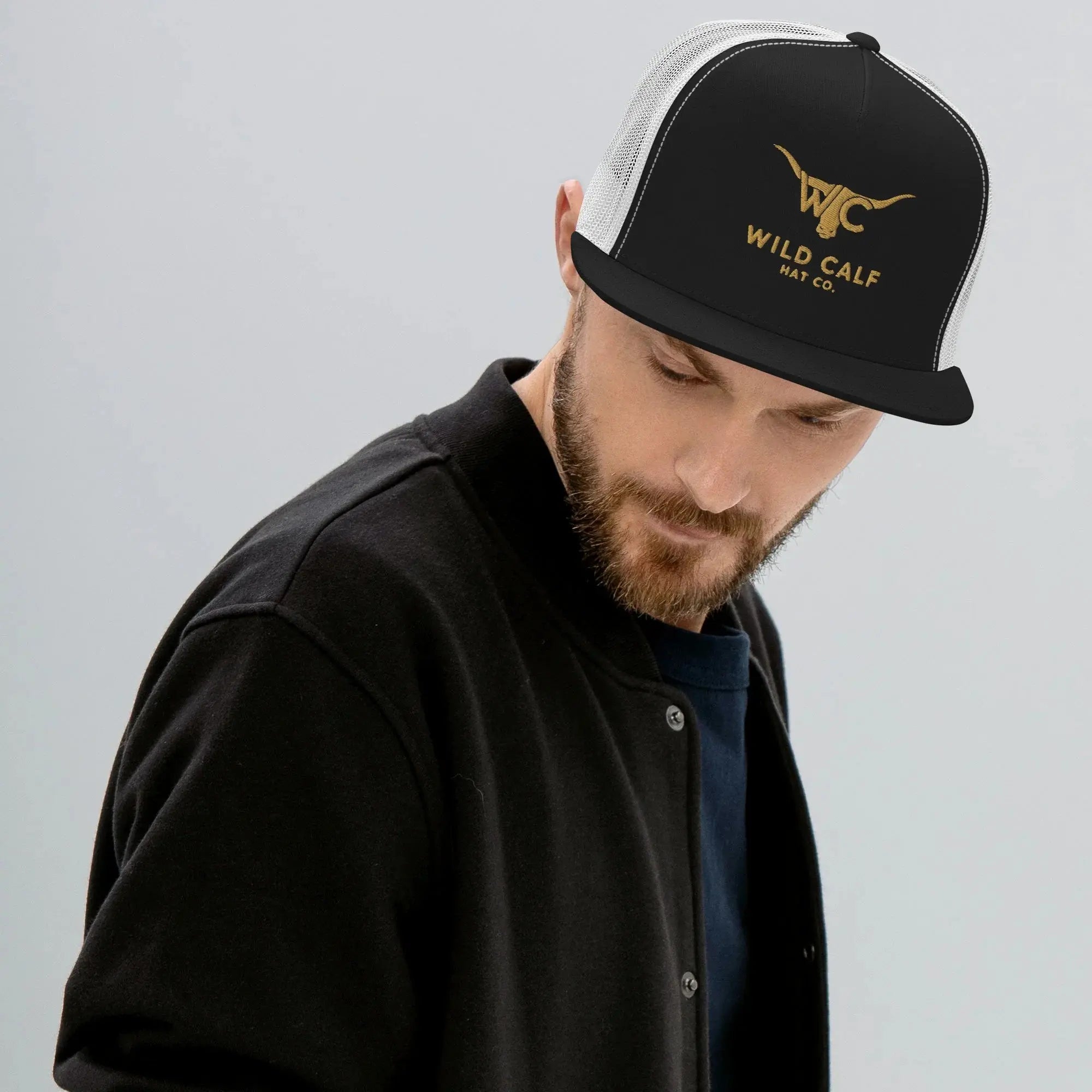 Man wearing a black and white western trucker cap with gold logo, modern professional style