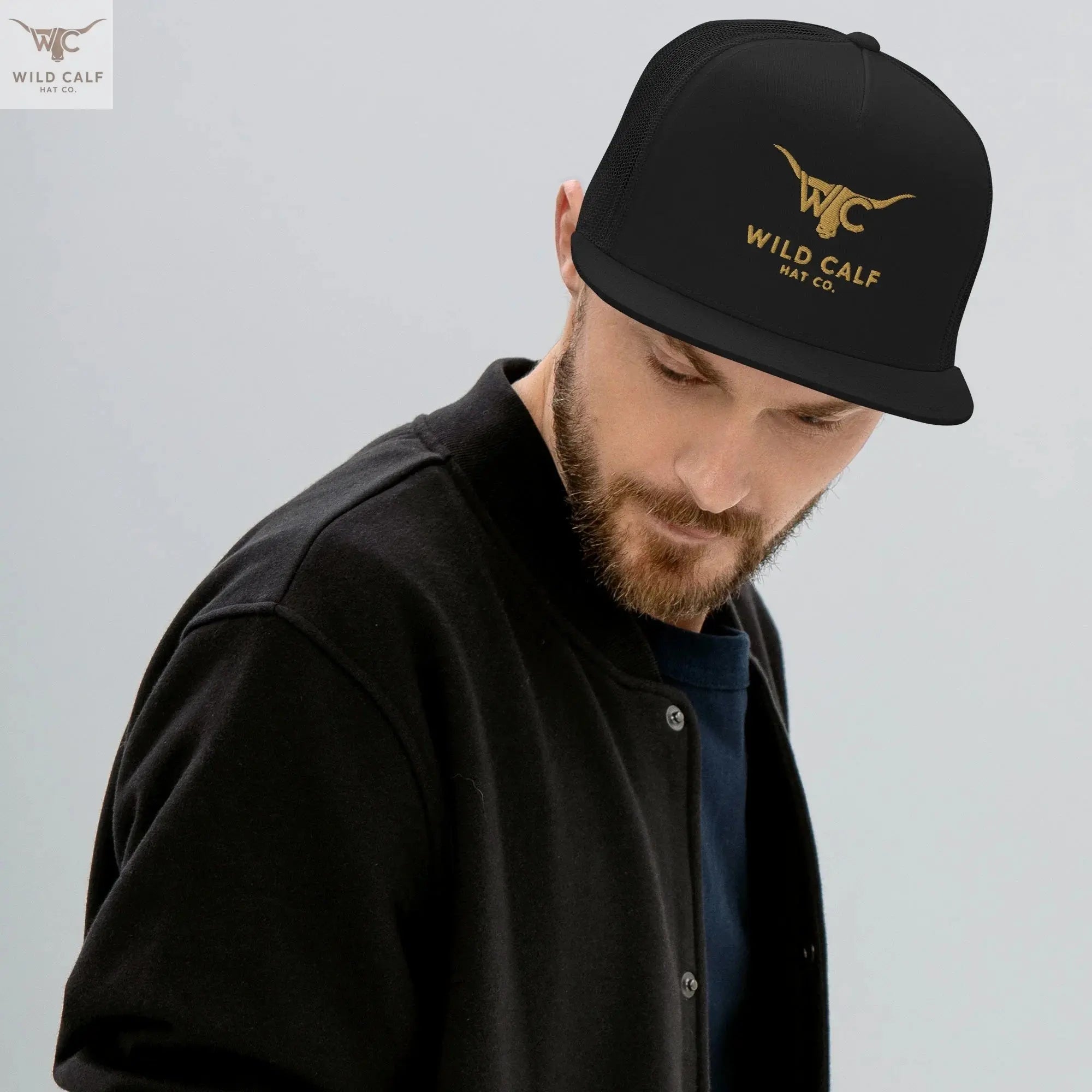 Man wearing black western trucker cap with gold logo and longhorn graphic, professional style