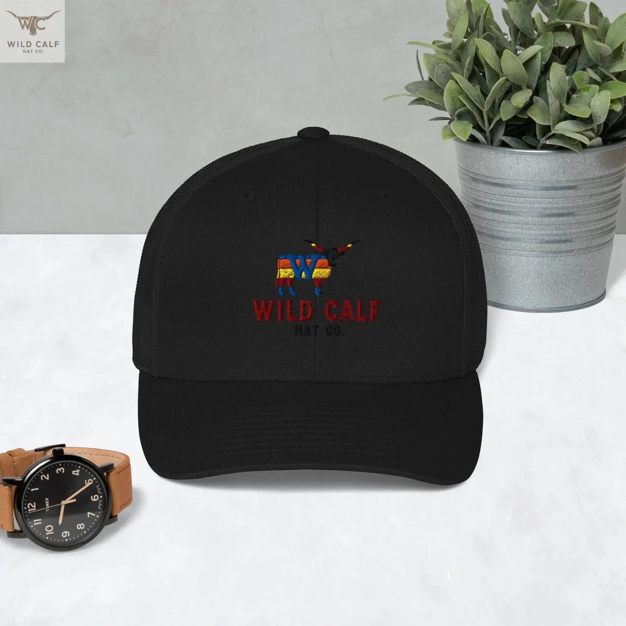 Black retro trucker hat with colorful western bull logo, styled on a marble surface.