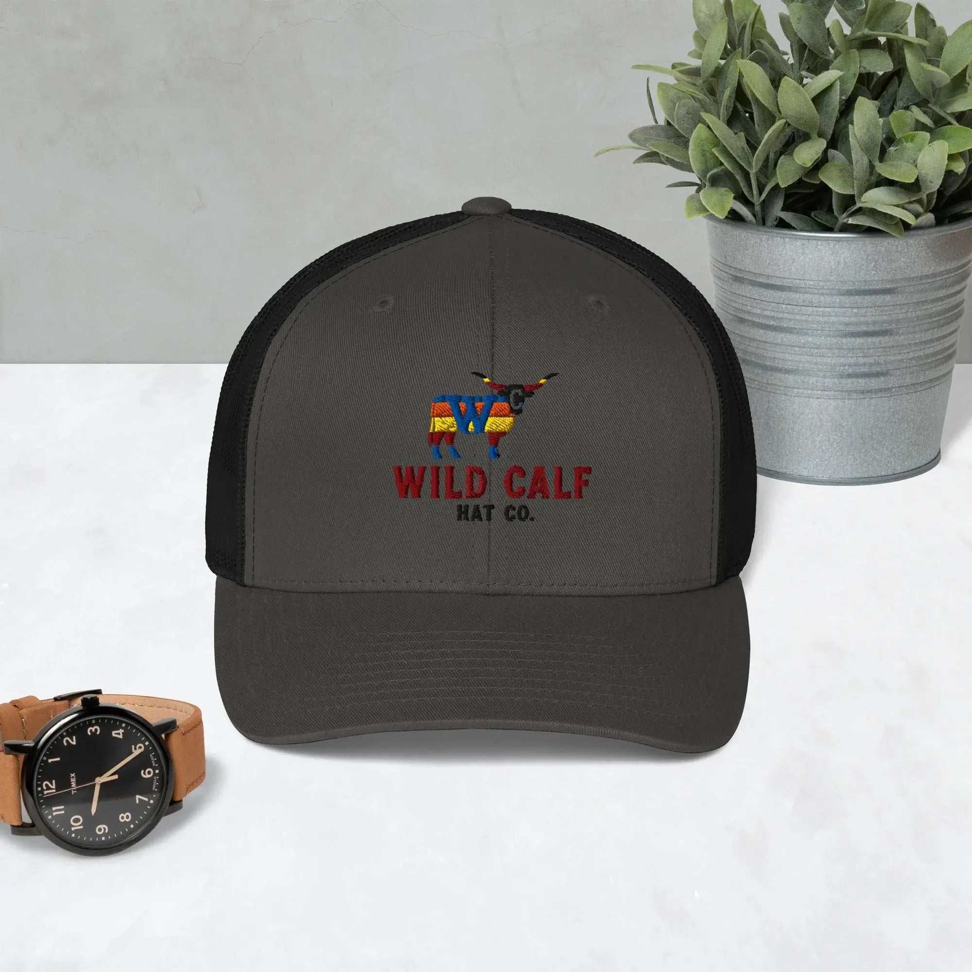 Charcoal and black western trucker hat with embroidered bull logo on a modern desk.